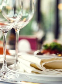 close up of table place settings with wine glasses in foreground